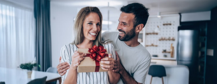 Casal feliz a trocar presentes do dia dos namorados, usufruindo das vantagens do Cartão BPI Classic.