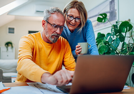 Pareja mirando la pantalla de un portátil. Soluciones BPI Particulares.