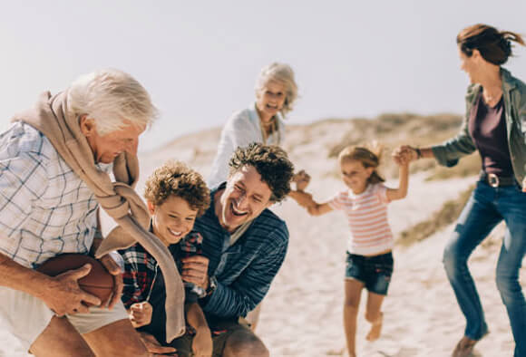 Family playing on the beach, with their future planned. BPI Capitalisation Insurance.