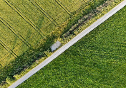 Vista área de um campo verdejante com uma estrada a meio. BPI Impacto Clima Obrigações.